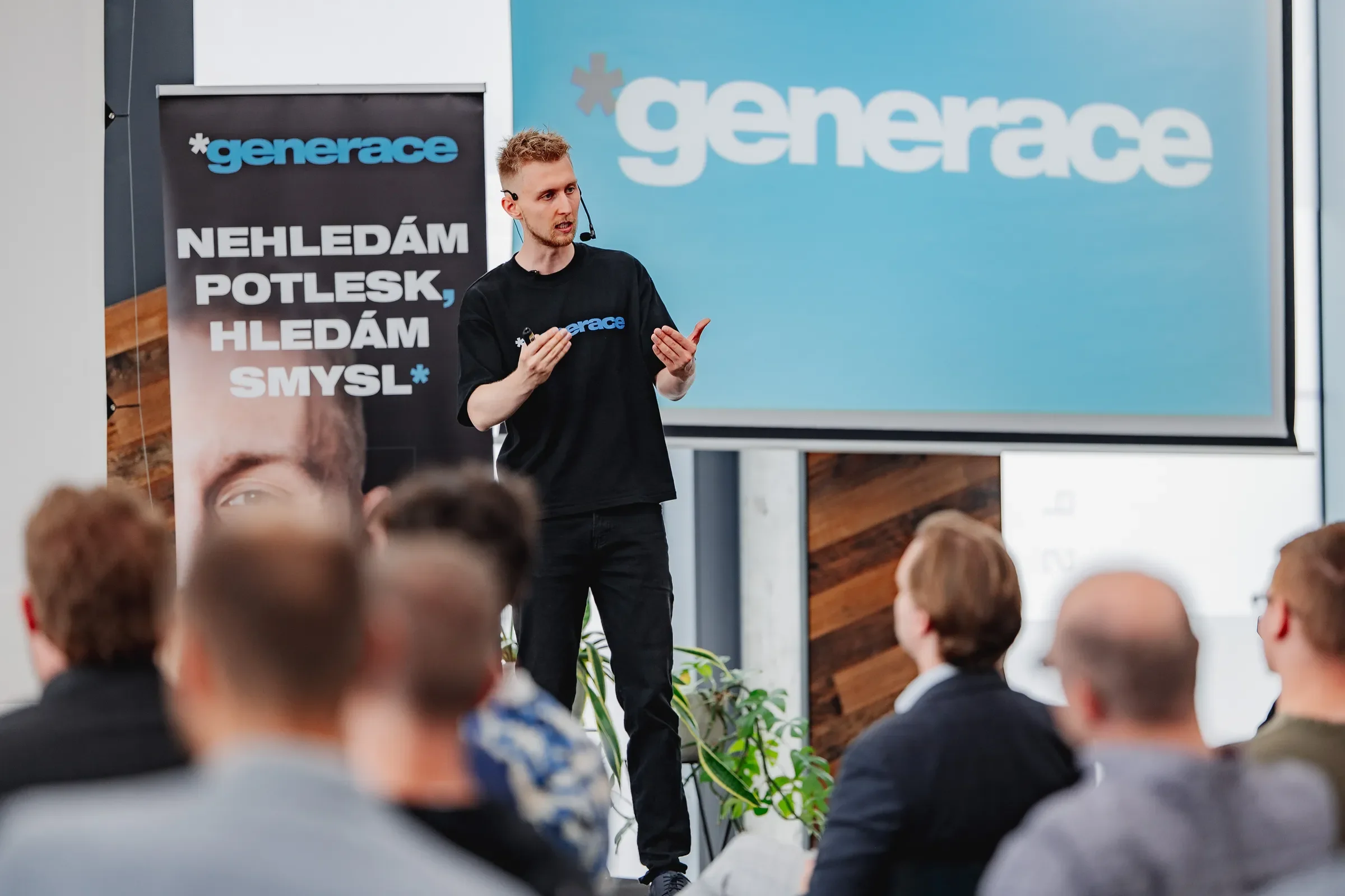 Daniel Krutý spricht auf der Bühne vor einer Leinwand mit dem Generace-Logo